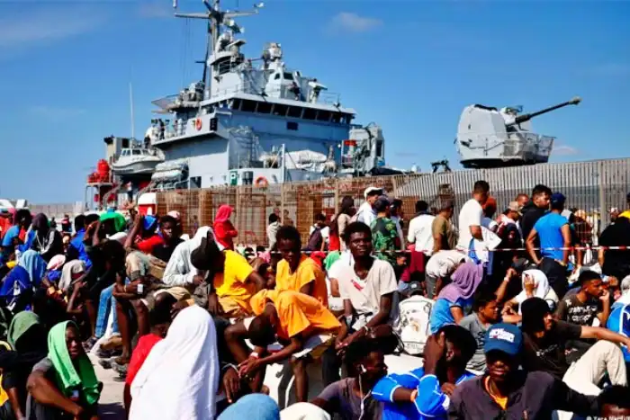 Fuerzas navales y migrantes en el puerto de una ciudad