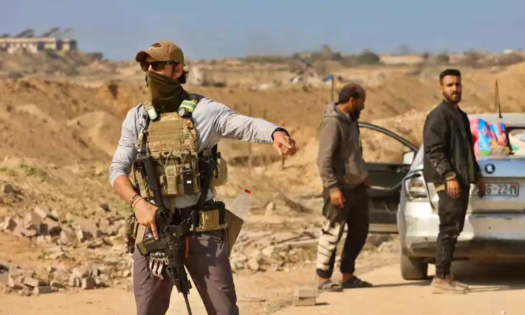 Un hombre armado hace un gesto en un puesto de control de seguridad estadounidense y egipcio en el corredor de Netzarim mientras los palestinos desplazados se dirigen desde el sur hacia el norte de la Franja de Gaza, el miércoles. Fotografía: Omar Al-Qattaa/AFP/Getty Images